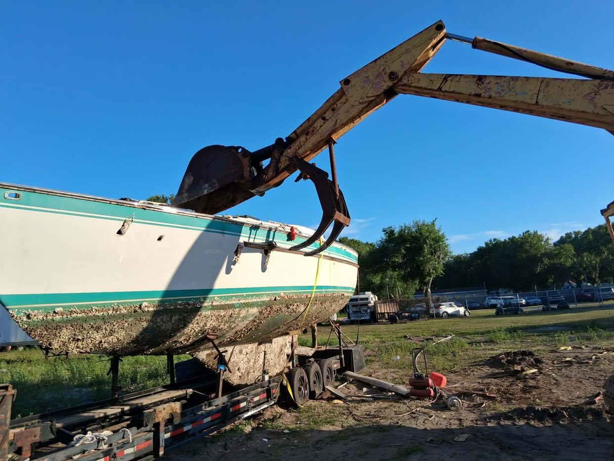 Excavator dismantling a boat at disposal site